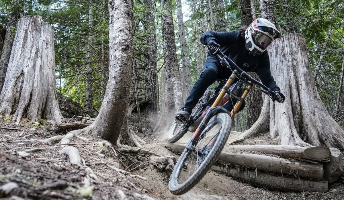 A mountain biker riding on rough terrain of tree roots. 