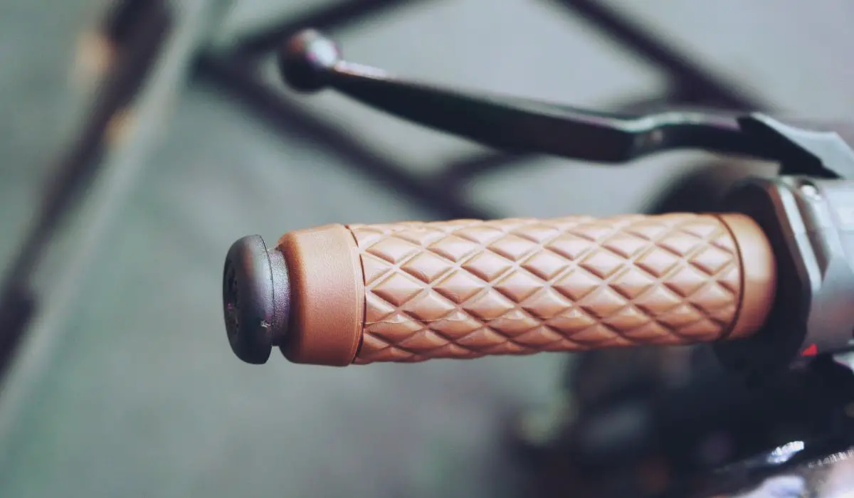 A bike handlebar with brown padded grips. 