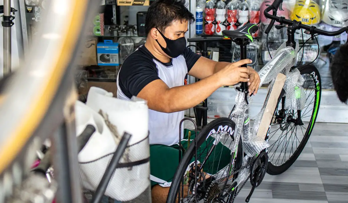 A man unwrapping a new bike at a bike shop, and adjusting the seat. 