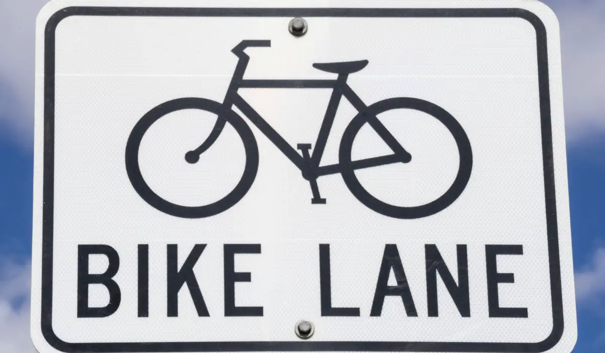 A white street sign with black text that has a bike and says bike lane. 