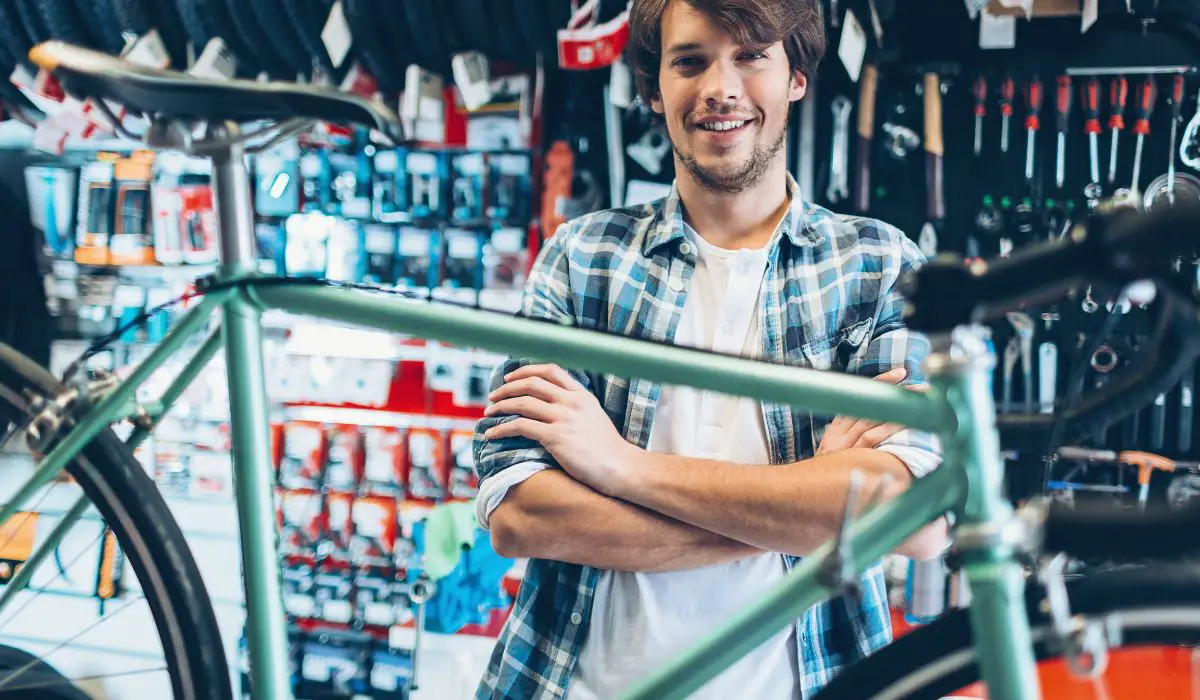 A man with his bike in a shop showing a painted sage green frame.