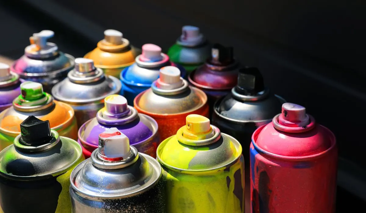 Cans of spray paint, with paint dripping down them to show the variety of colors.