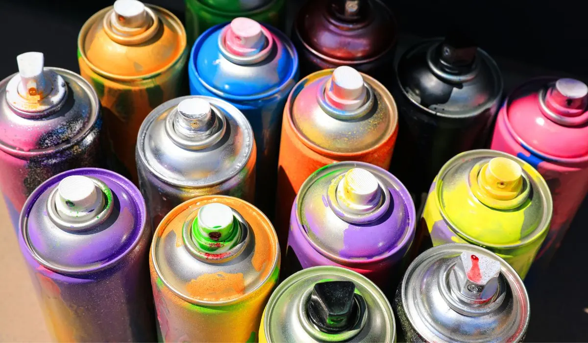 Top side view of cans of spray paint, dripping to show the various colors.