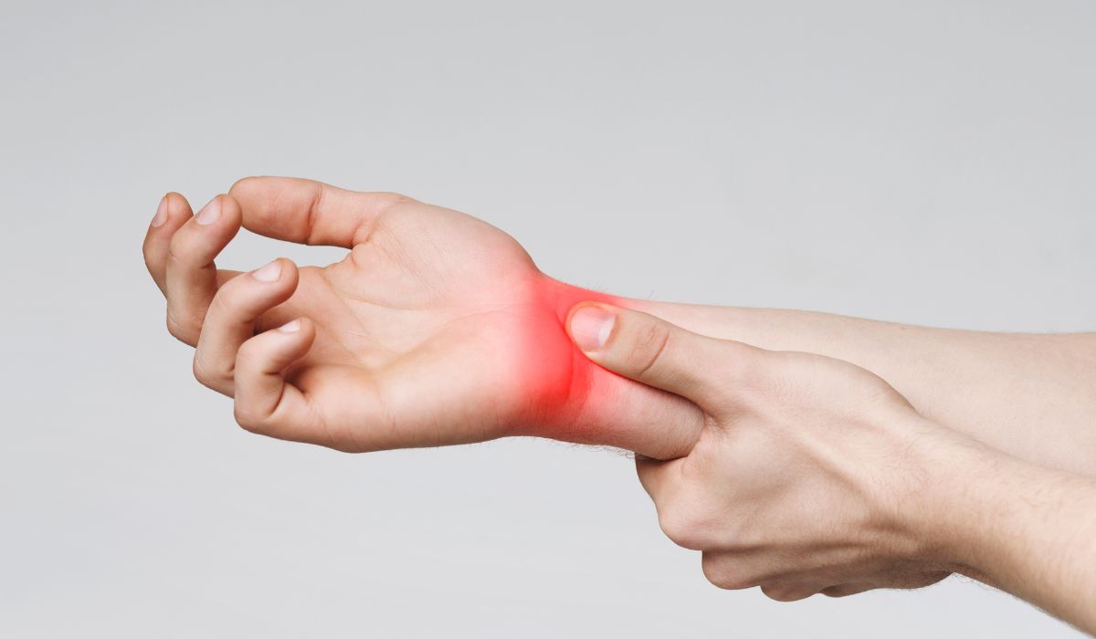 A person holding their wrist that is glowing red in pain showing where carpal tunnel is. 