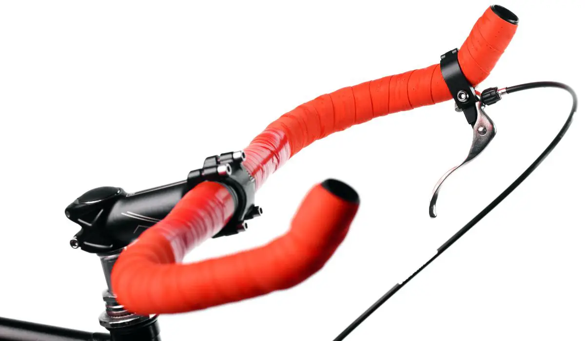 Bike handlebars wrapped in red padded tape that are upswept to a different angle. 