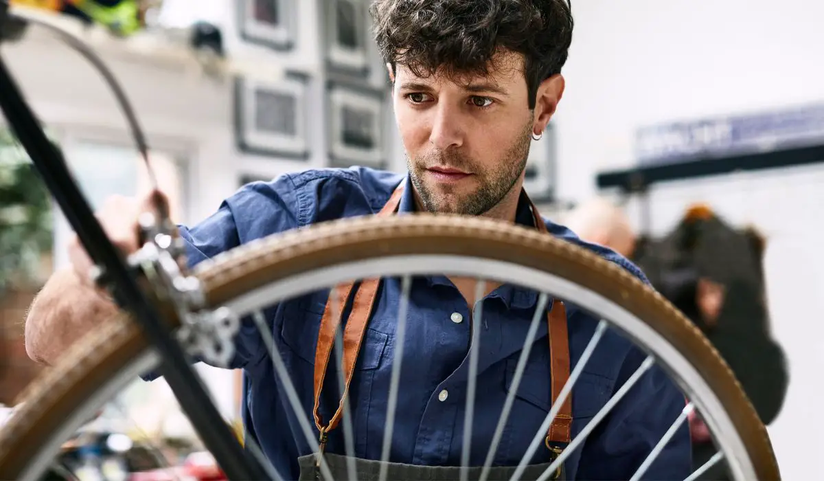A man checking the brakes on a bike wheel.