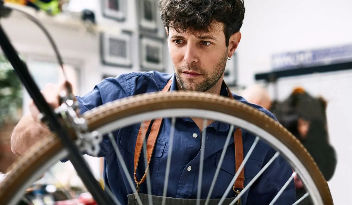 A man checking the brakes on a bike wheel.