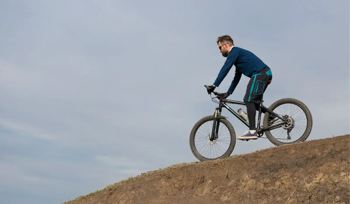 A man riding a mountain bike down a seep dirt hill. 