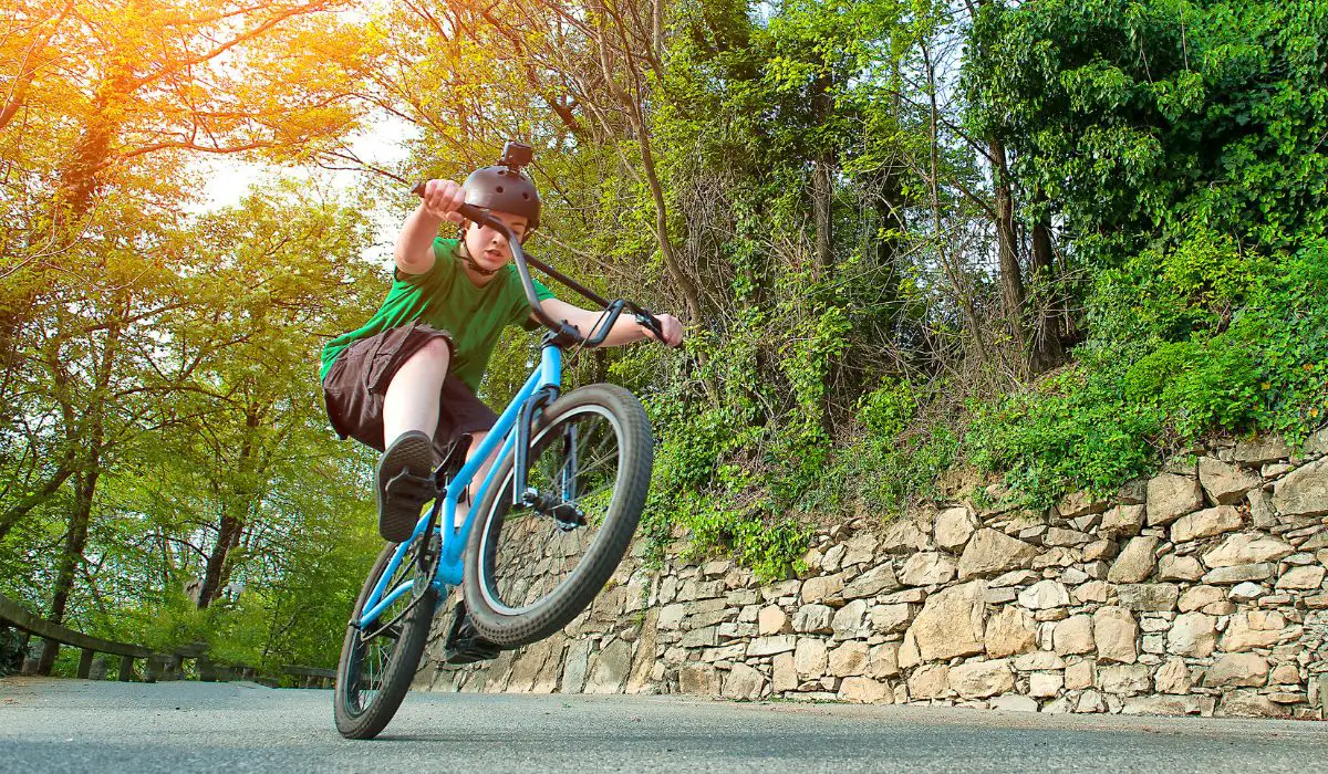 A kid with a helmet doing a bike trick. 