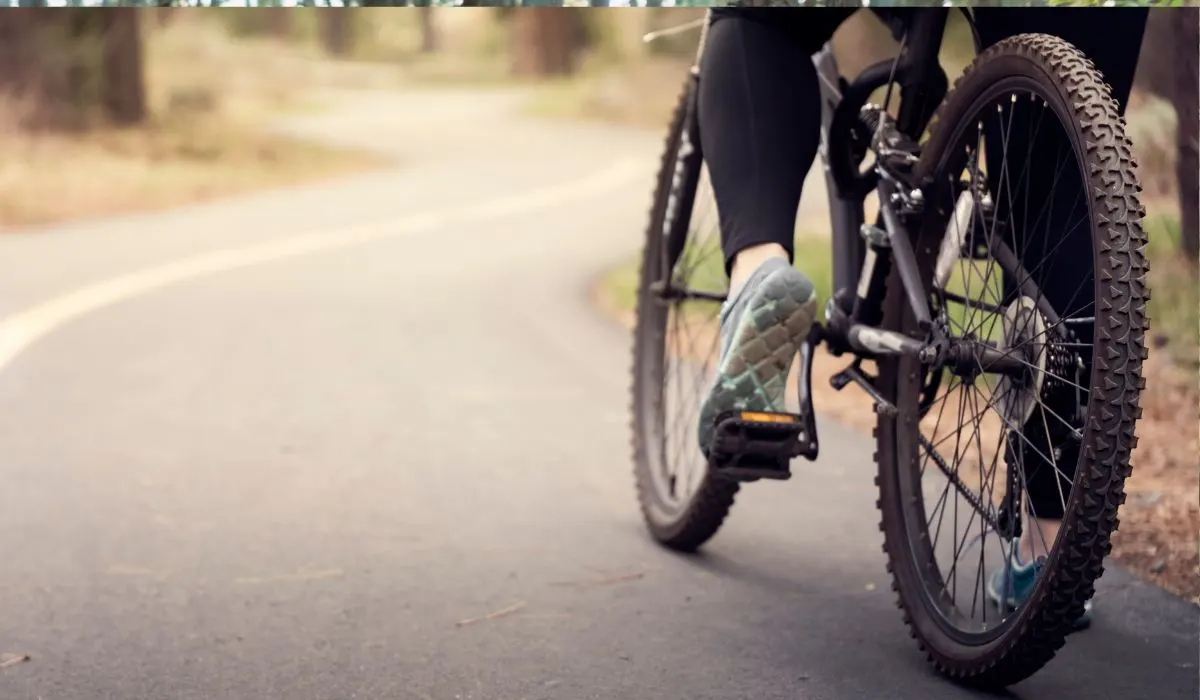 A bike being ridden on a road, wheels view. 