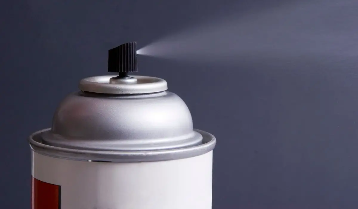 A can of spray spraying into the air with a dark background.