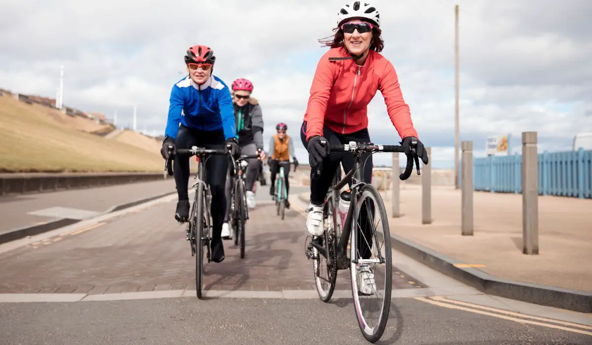 A group of people cycling with helmets, gloves, and sunglasses on. 