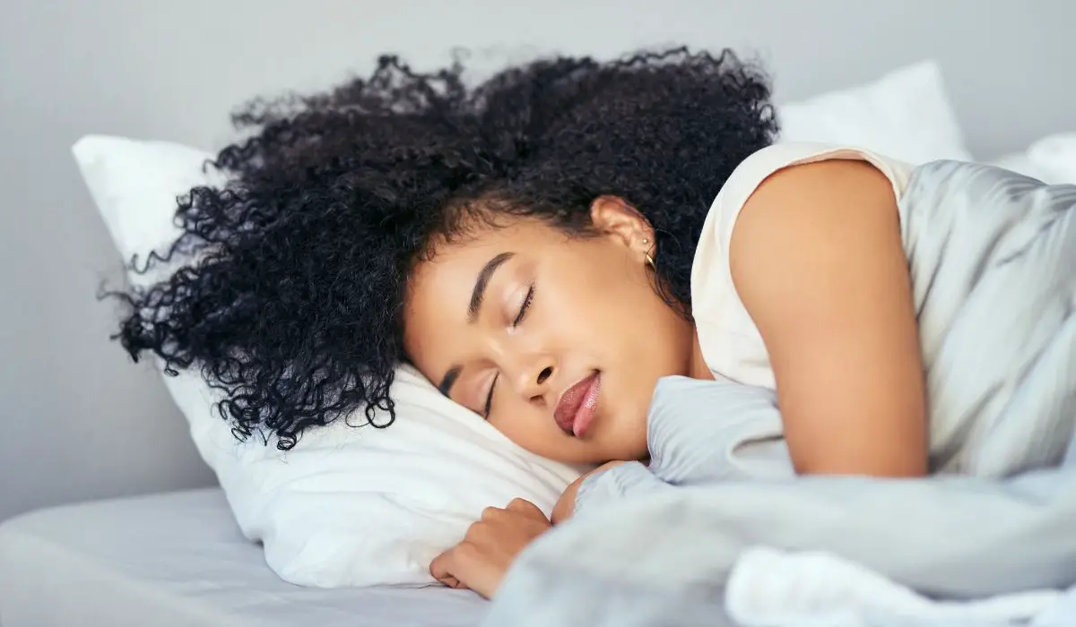 A woman sleeping in a bed on her side. 