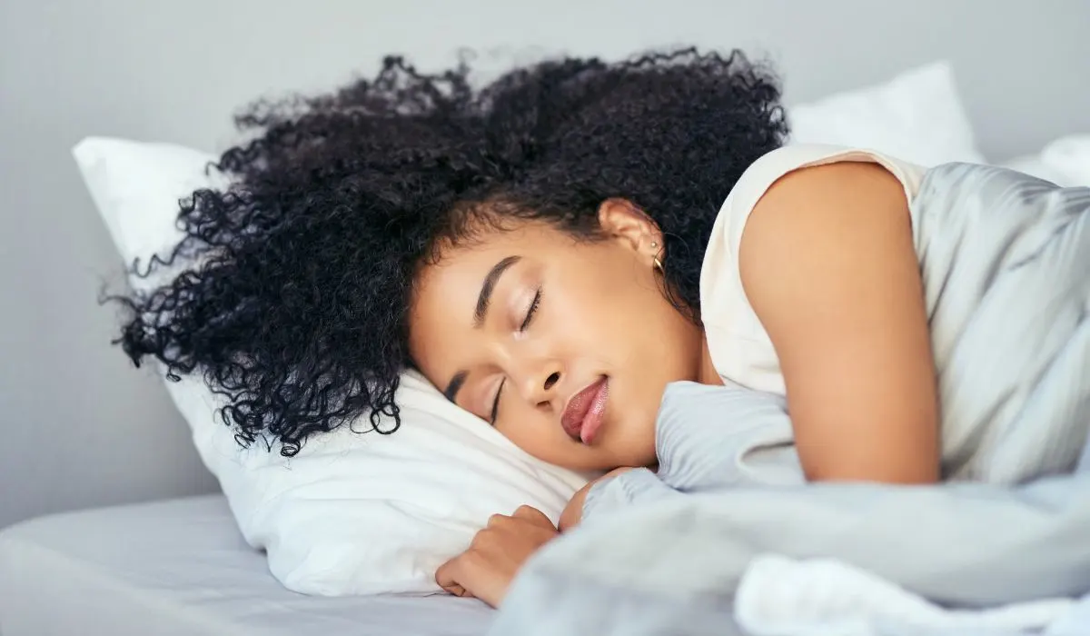 A woman sleeping in a bed on her side. 