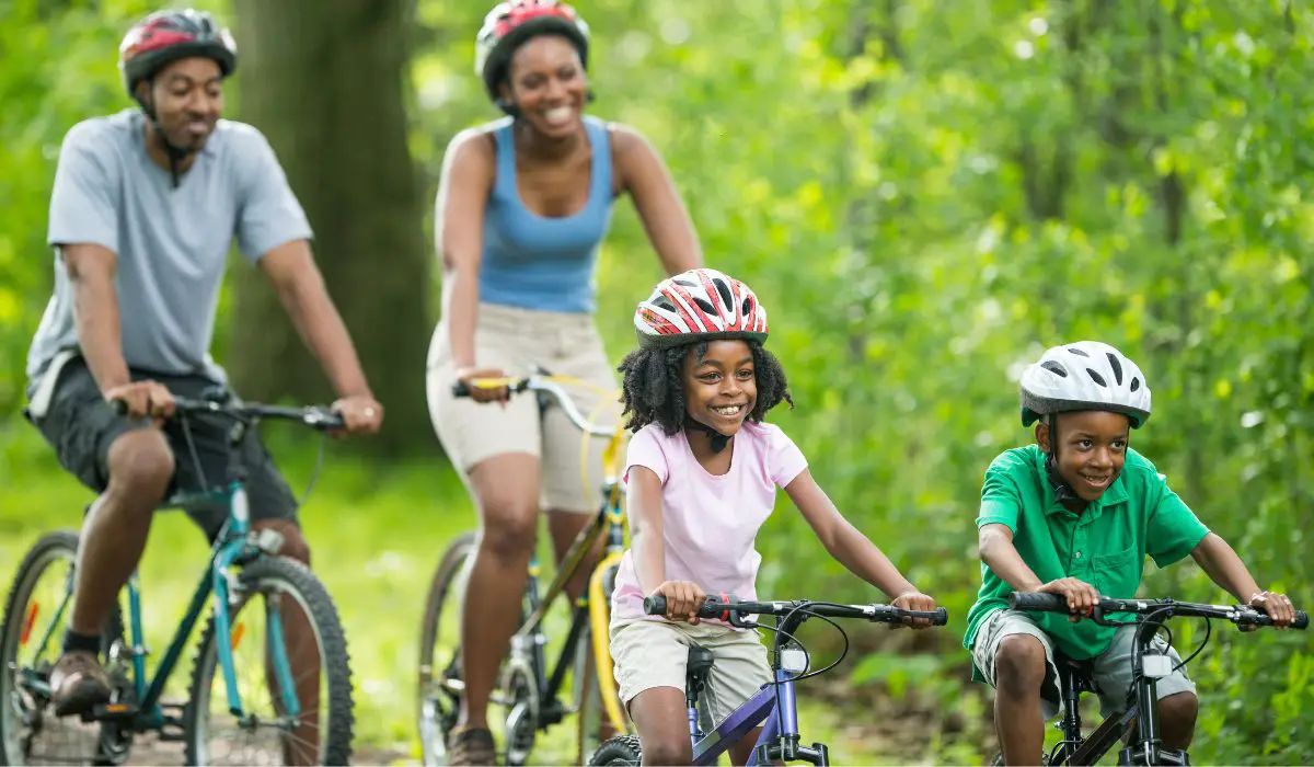 A family of 2 adults and 2 children all riding bikes and looking happy. 