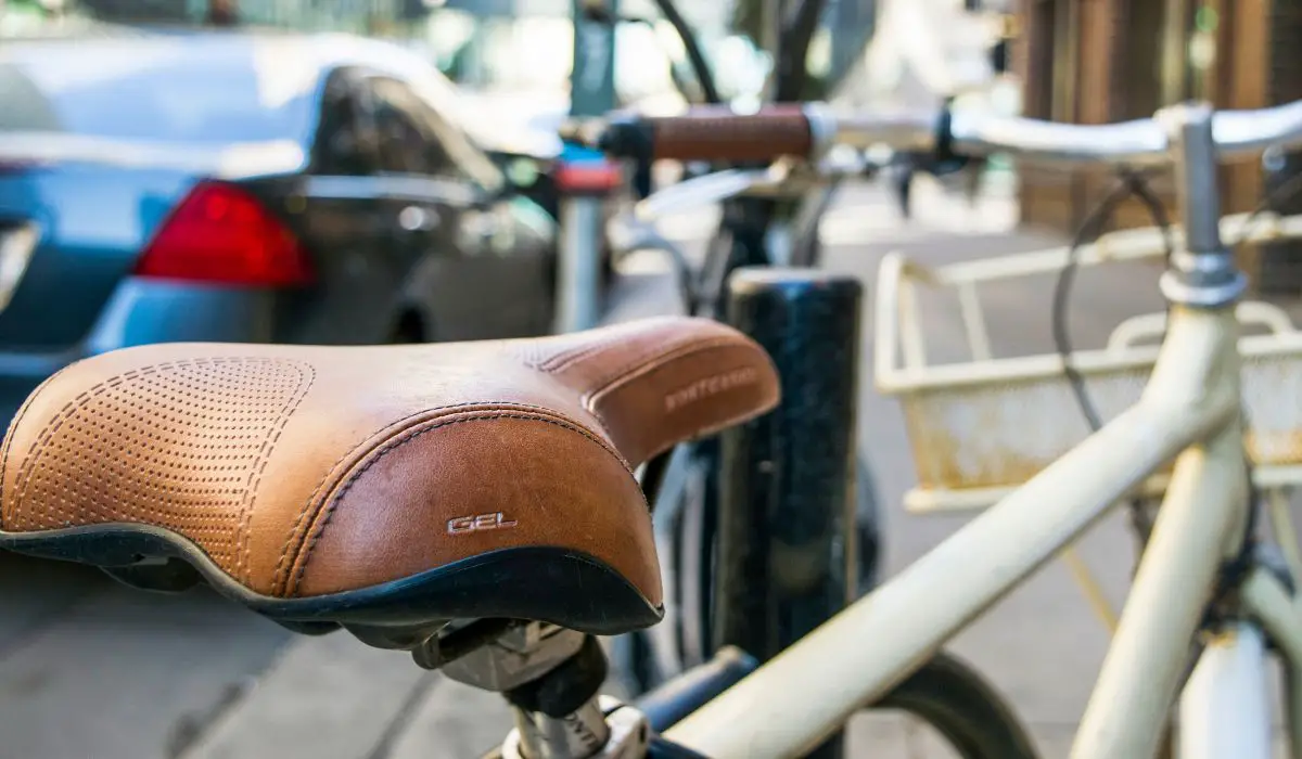 A white bike with a brown leather wide and thick bike seat that says GEL on it. 