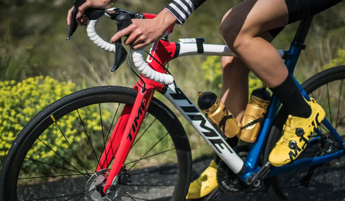 The hands and legs of a person on a bike, showing that the seat appears higher than the handlebars. 