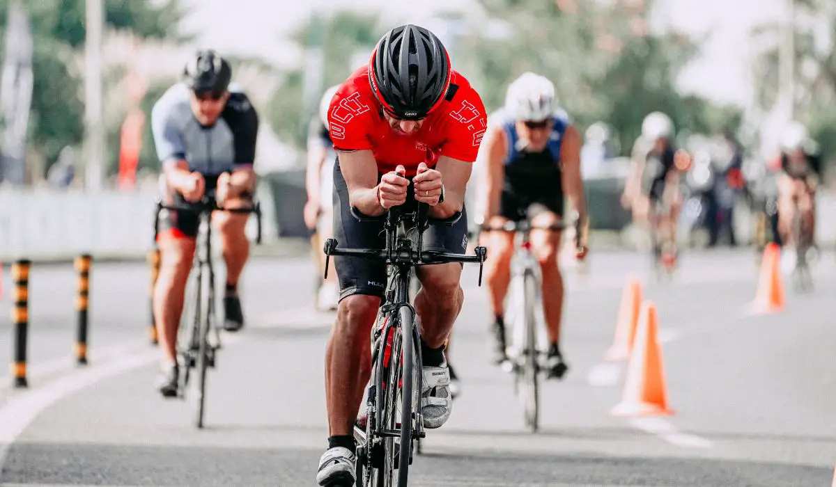 A road bike race with a man hunched over his handlebars, riding fast.