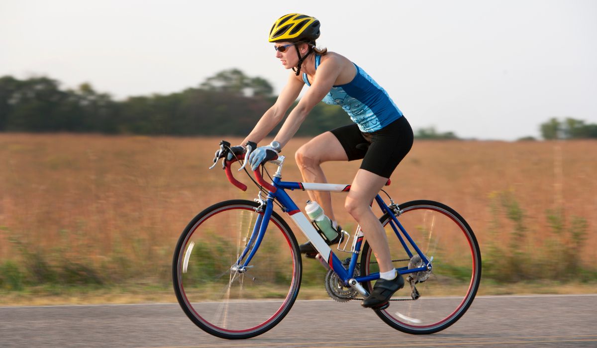  A woman on a road bike in the country with good posture and technique. 