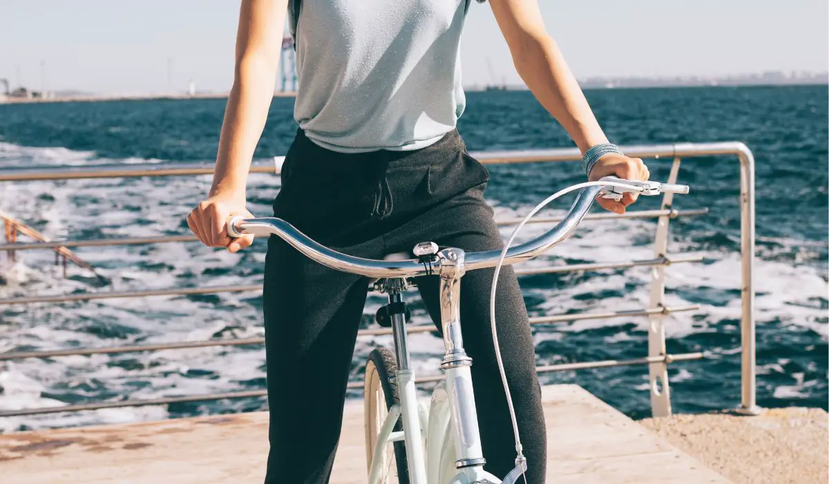 A person on a cruiser bike with handlebars swept back for easy reach, with the ocean in the background. 