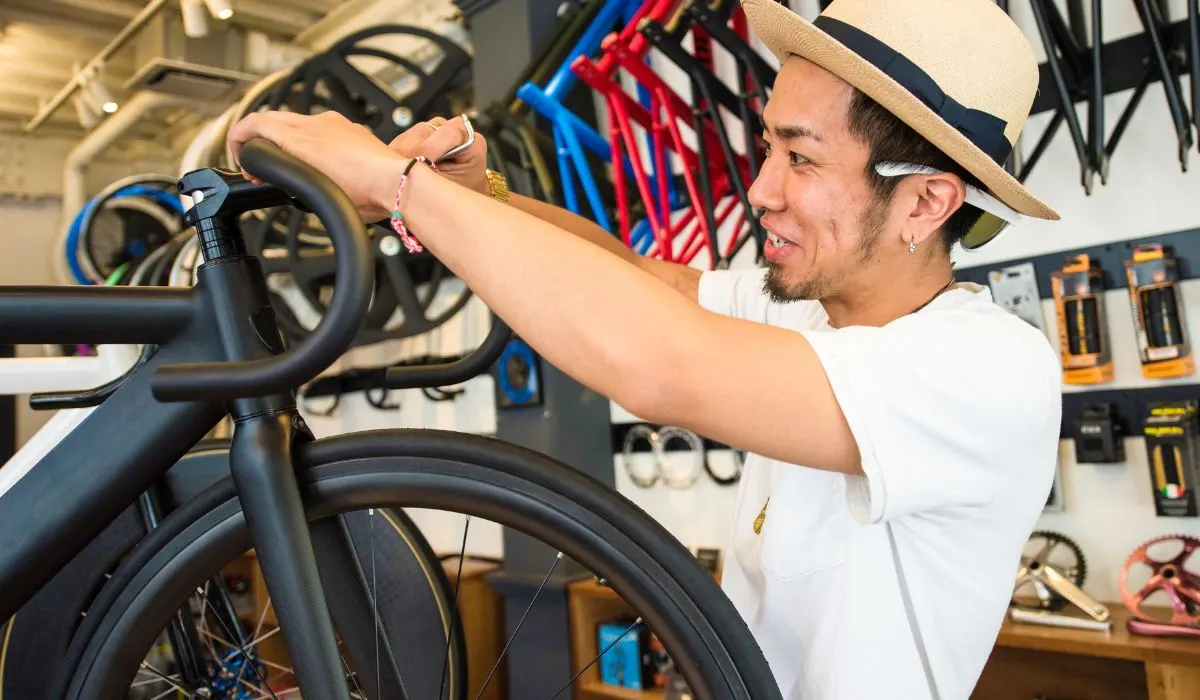 A man in a bike garage changing the handlebars of a bike.