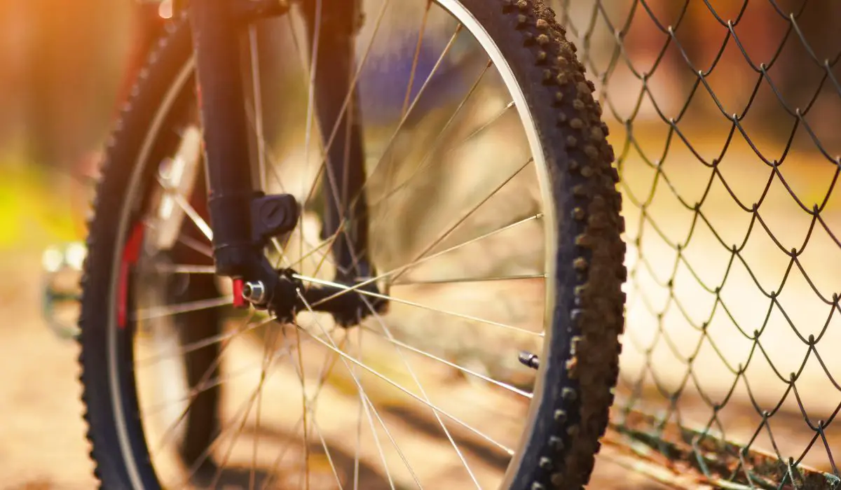 A close up of a bike wheel outside in the sunlight. 