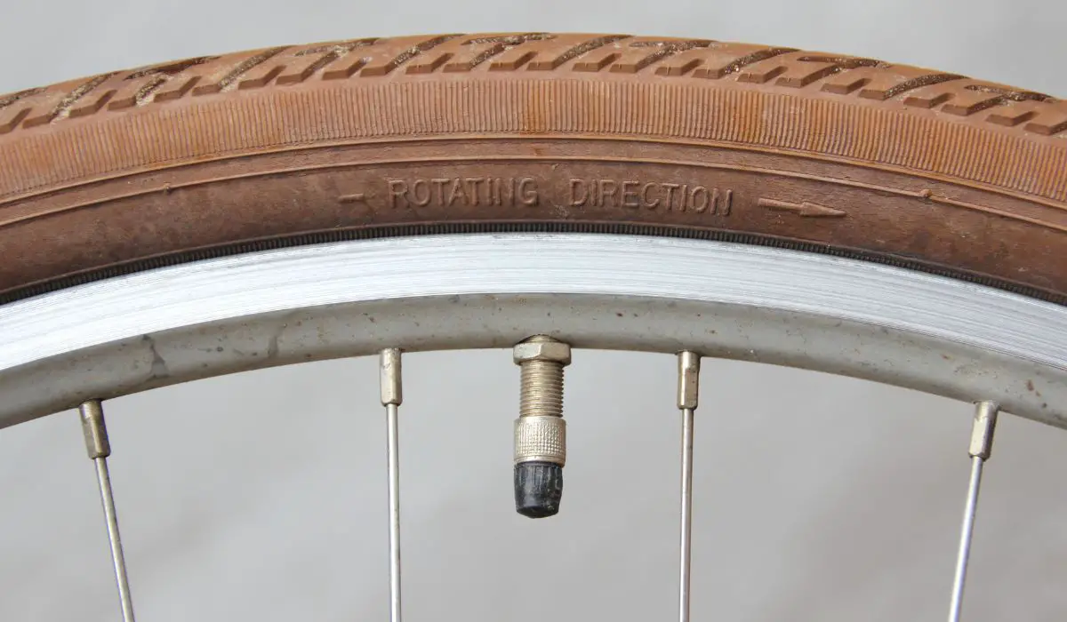 A brown bike tire with the valve pointed downward.