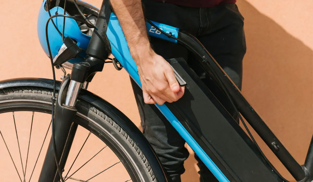 A person checking the electrical mechanics on the body of an electric bike.