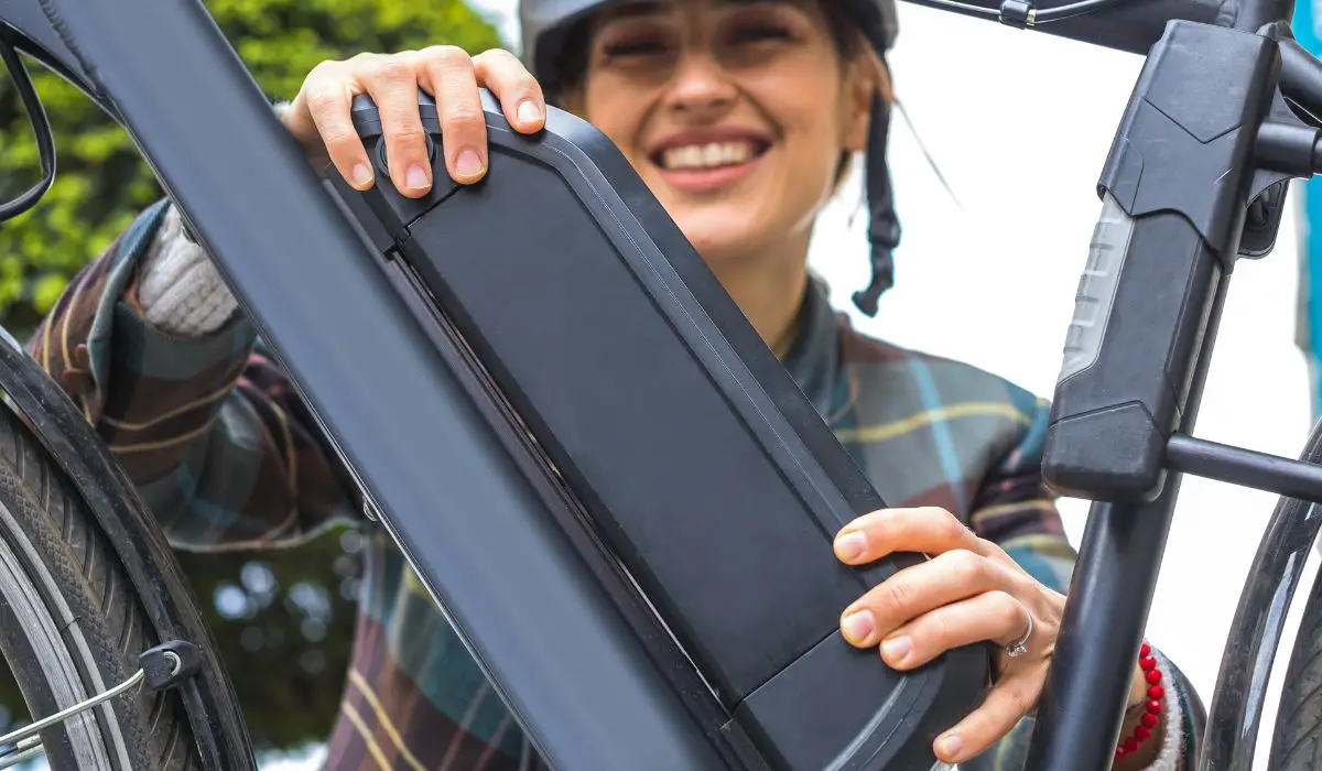 A woman checking the battery connected to her electric bike. 