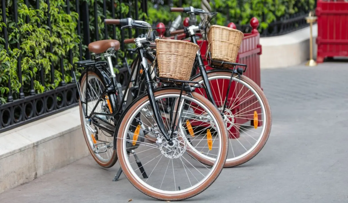 2 city bikes with brown seats and wheels with baskets in the front. 