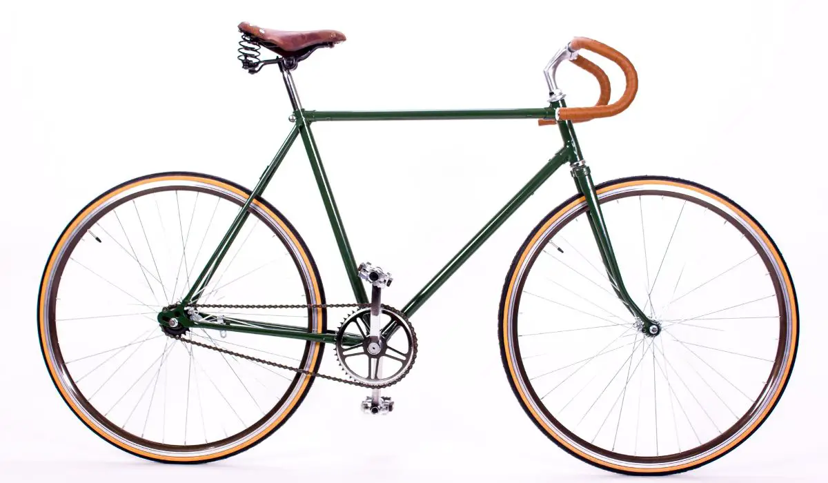A retro city bike, dark green with brown leather seat and handlebars.
