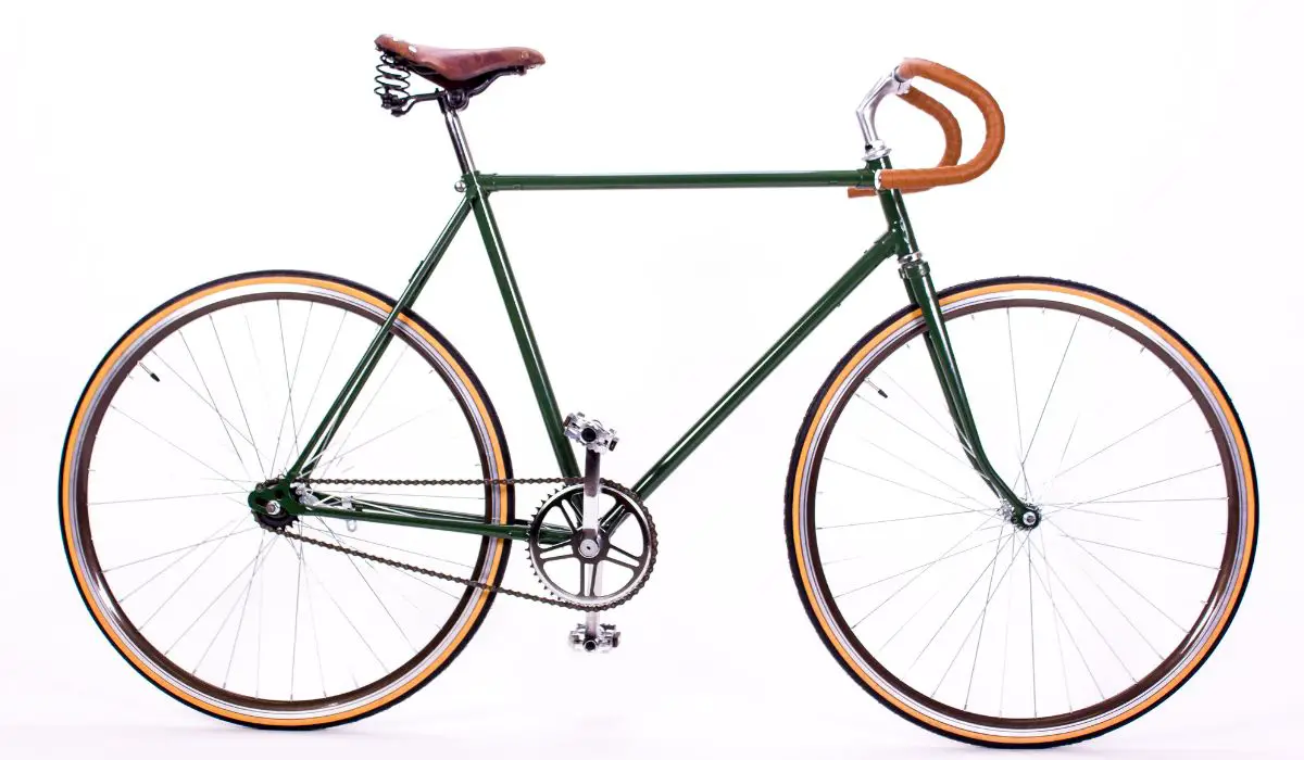 A retro city bike, dark green with brown leather seat and handlebars. 