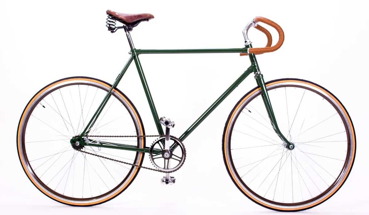 A retro city bike, dark green with brown leather seat and handlebars.
