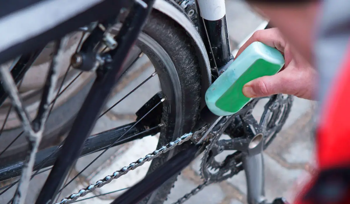 A person lubricating the chain on their bike. 