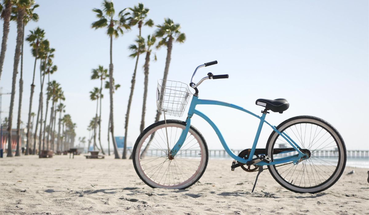A blue beach cruiser bike on a beach with palm trees.
