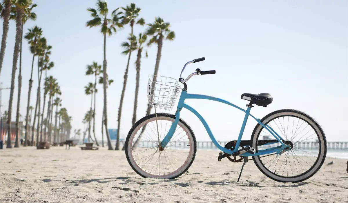 A blue beach cruiser bike on a beach with palm trees. 