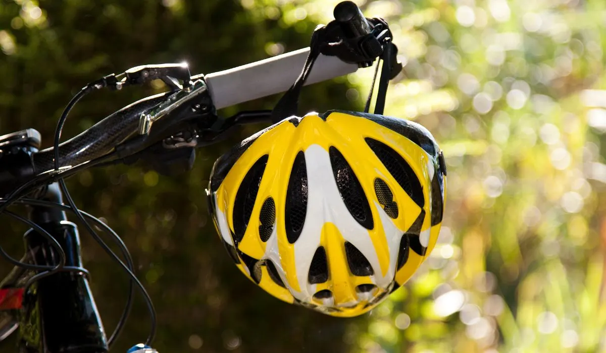 A yellow bike helmet hanging from bike handlebars.