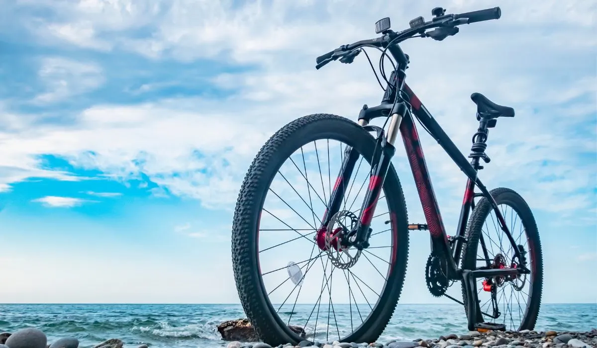 A mountain bike on rocks near the ocean with the sky in the background. 