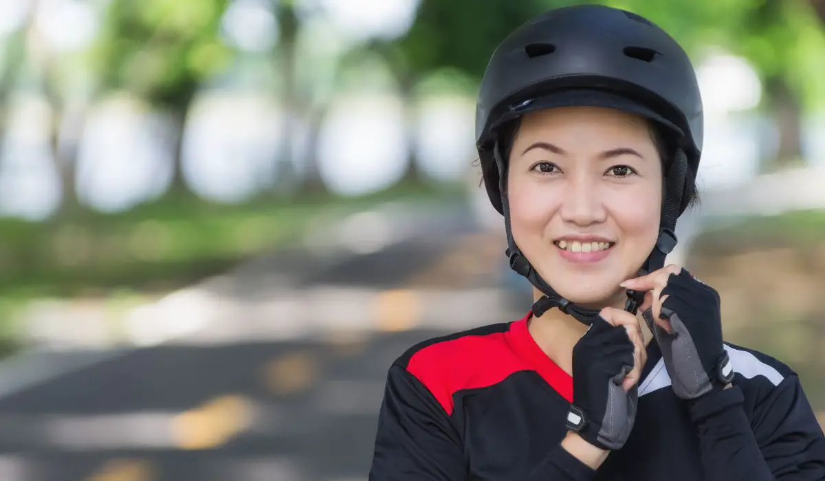 A woman buckling a bike helmet under her chin.