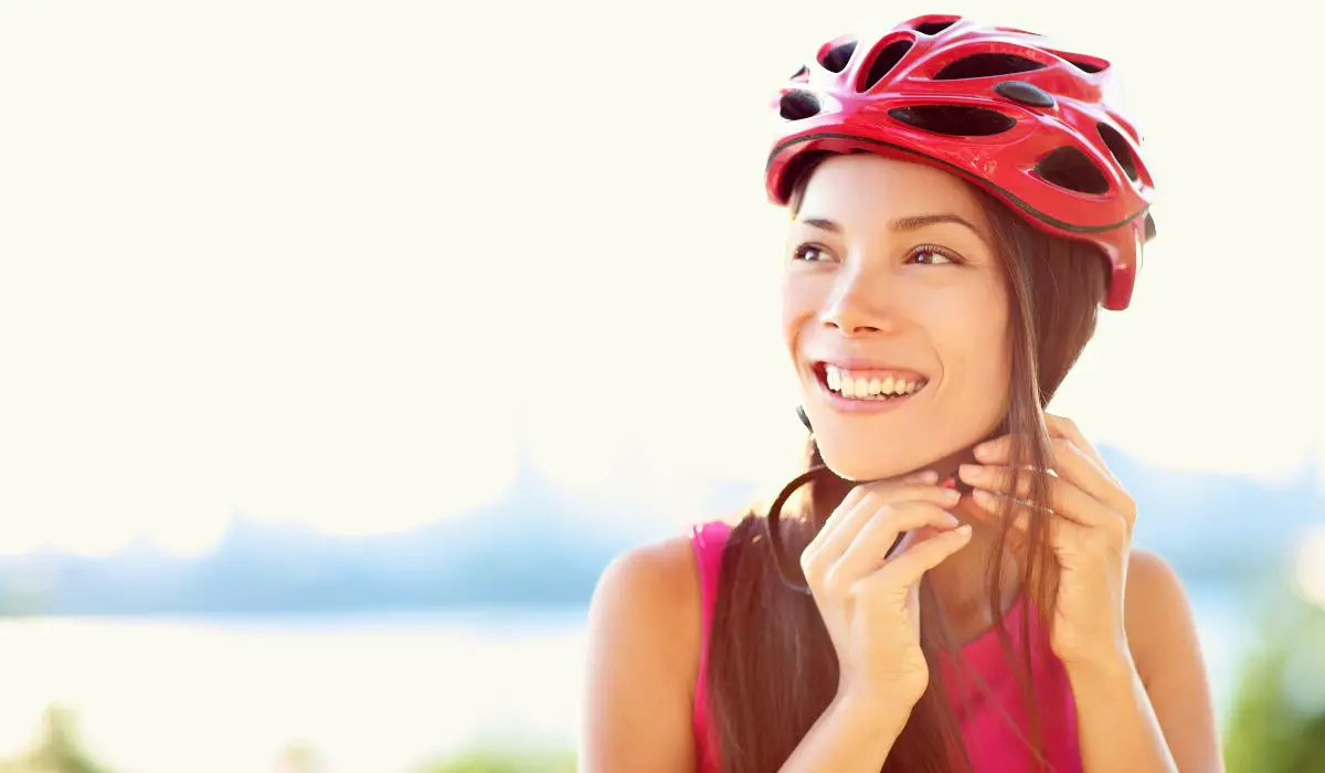 A woman strapping on a helmet.