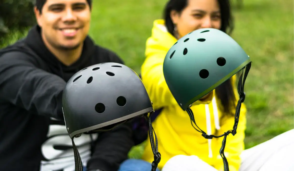 Teens holding out their bike helmets in front view.