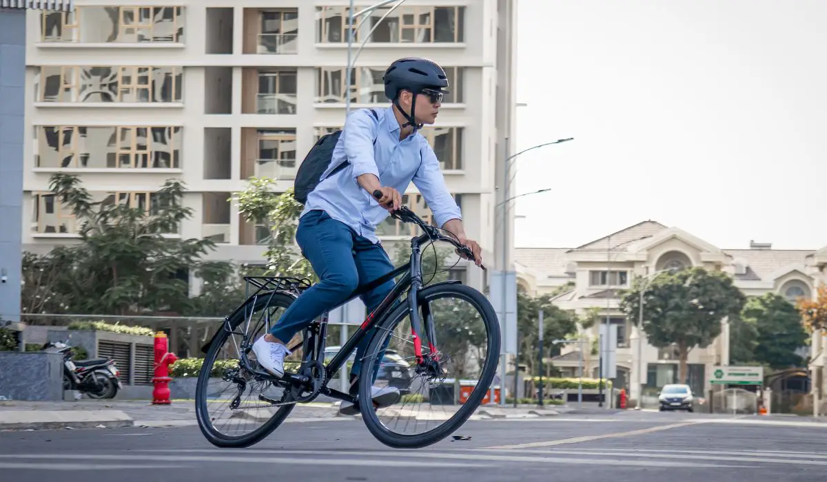 A man with a backpack riding his bike in an urban area. 