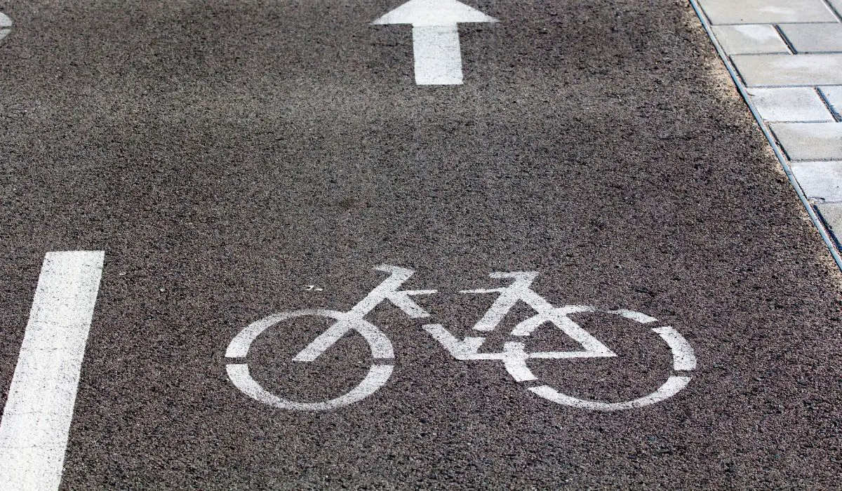 Black pavement with a white bike spray painted signifying a bike lane. 