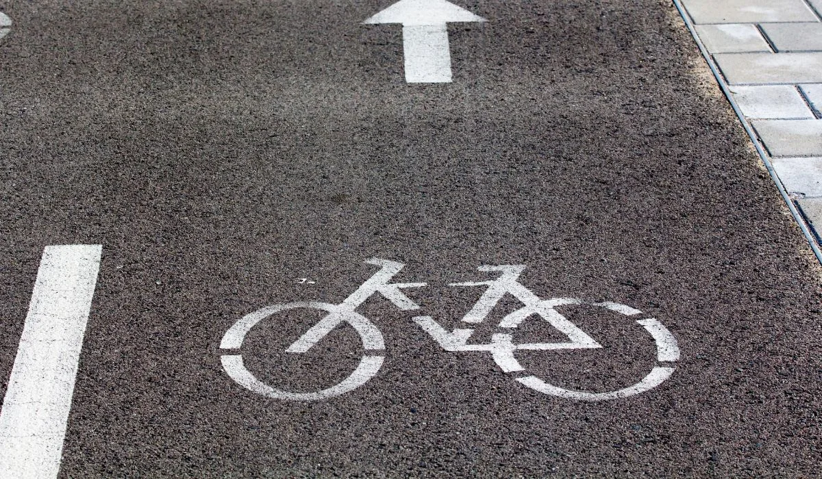 Black pavement with a white bike spray painted signifying a bike lane. 