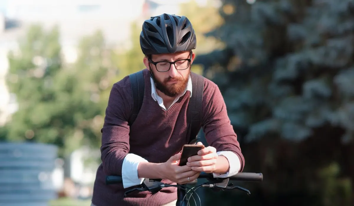 A man stopped on his bike looking at his phone. 