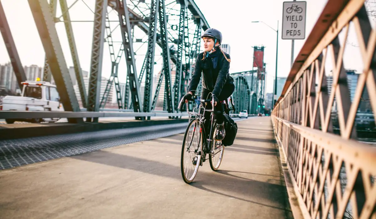 A woman commuting to work on her bike riding over a city bridge. 
