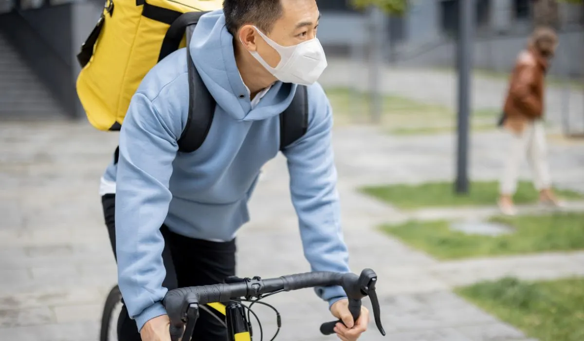 A man riding a bike with a mask on.