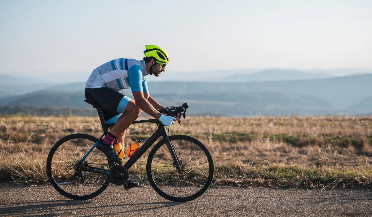 A man on a road bike with a cycling jersey that is short sleeved and well fitted. 