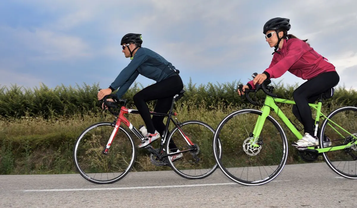 A man and woman on  bikes both with long sleeved jerseys. 