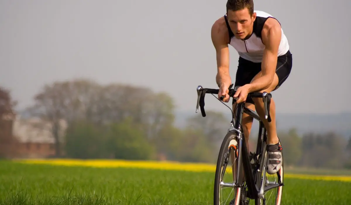A man cycling with a sleeveless jersey. 